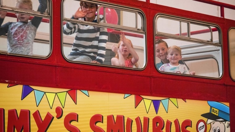 Lachende kinderen bovenin de smulbus om te gaan eten tijdens een kinderfeestje