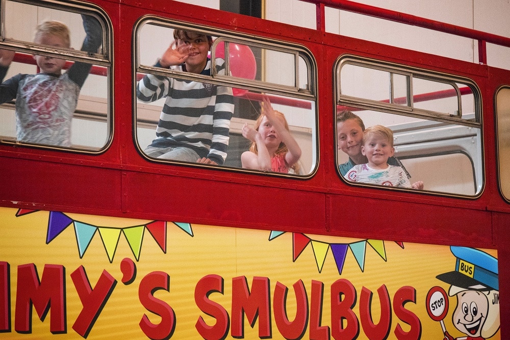 Lachende kinderen bovenin de smulbus om te gaan eten tijdens een kinderfeestje