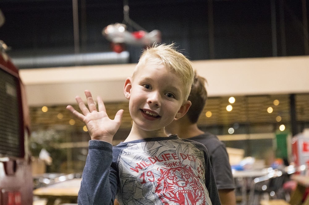 Jongen zwaait met lach in het speelparadijs