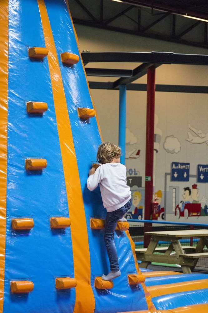 Jongen klimt op de wand van het springkussen naar boven