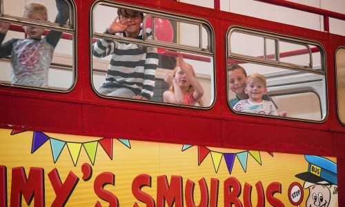 Lachende kinderen bovenin de smulbus om te gaan eten tijdens een kinderfeestje